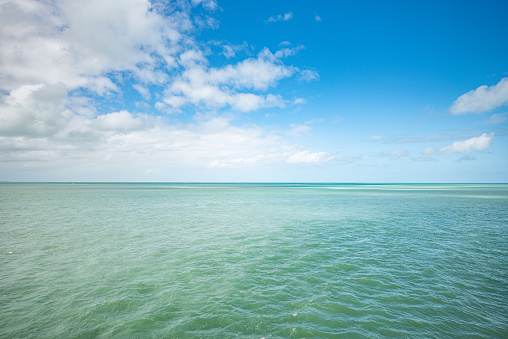 Ocean view from the Florida Keys. The water is a turkoise color and the sky is blue with a few clouds showing. The weather was warm when this photo was taken.