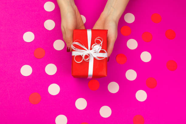 istock Woman hands holding gift box on pink background 1427607642