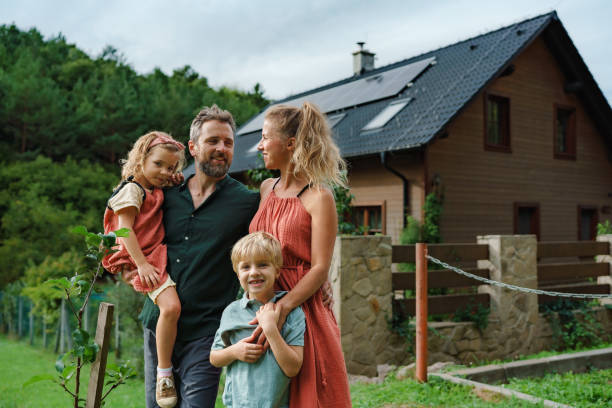 Happy family near their house with solar panels. Alternative energy, saving resources and sustainable lifestyle concept. stock photo