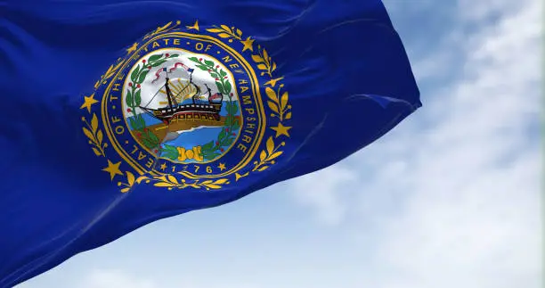 The flag of New Hampshire state flag waving in the wind. New Hampshire is a state in the New England region of the northeastern United States. Us state flag