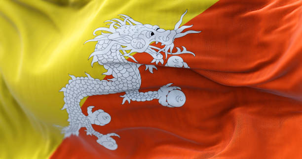Close-up view of the Bhutan national flag waving in the wind Close-up view of the Bhutan national flag waving in the wind. The Kingdom of Bhutan is a landlocked country in the Eastern Himalayas. Fabric textured background. Selective focus bhutanese culture photos stock pictures, royalty-free photos & images