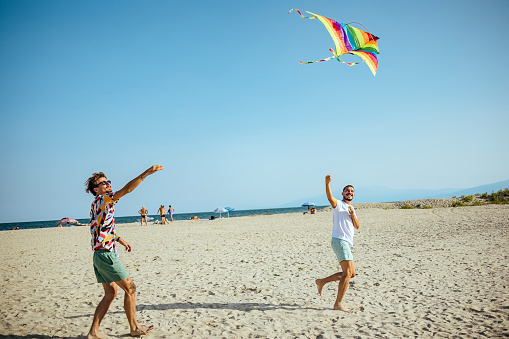 Friends playing and flying kite at beach in weekend.