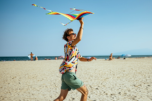 Man playing and flying kite at beach in weekend.