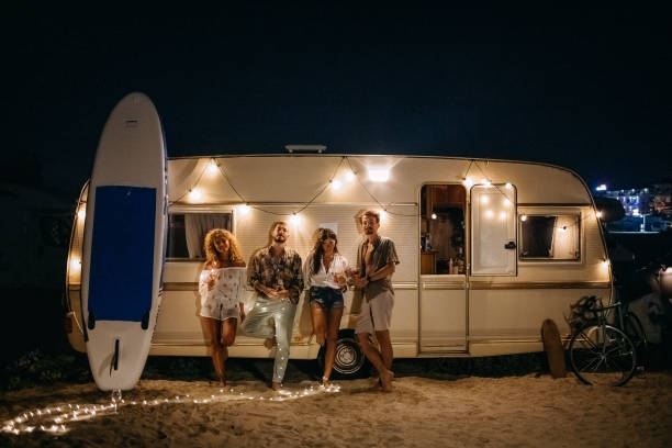Portrait of young friends Portrait of young friends leaning against a caravan looking into the camera camper trailer photos stock pictures, royalty-free photos & images