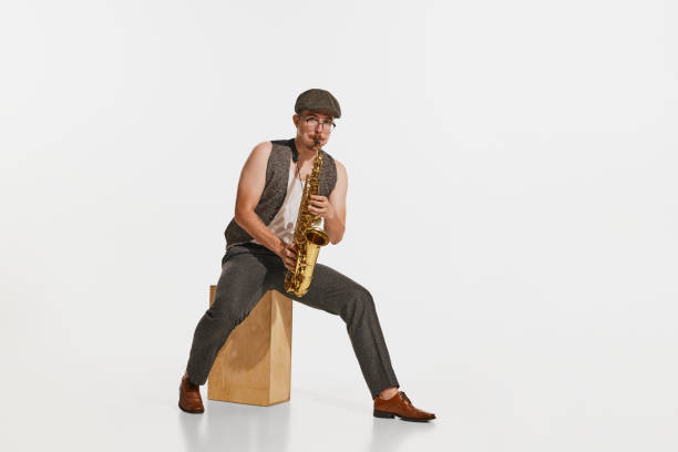 Soul music. Young musician in retro style outfit playing saxophone isolated over white studio background. Concept of music, hobby, festival.