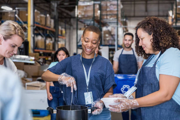 voluntarios de grupos multirraciales en el comedor de beneficencia del banco de alimentos - homelessness men white black fotografías e imágenes de stock