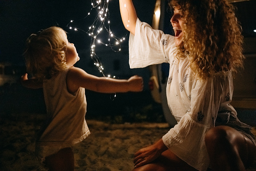 Mother enjoys with her baby at night on the beach