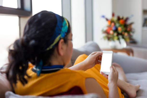 istock Young woman hold mobile phone in hands, lying on the sofa 1427625071