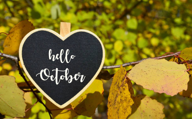 Hello October greeting with decorative heart with text on a yellow leaves background.Fall season concept. stock photo