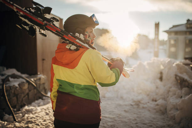 Female skier standing on a hill and carrying her skies in ski resort.