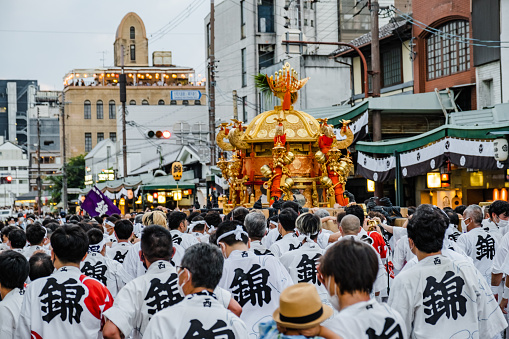 Kyoto, Japan - July 17, 2022: Large group of people walking on the street with the Mikoshi in late afternoon during the Gion Festival