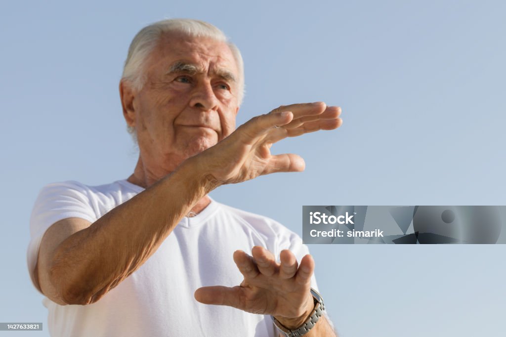 Tai Chi Senior man is doing tai chi with clear sky in background. Qi Gong Stock Photo