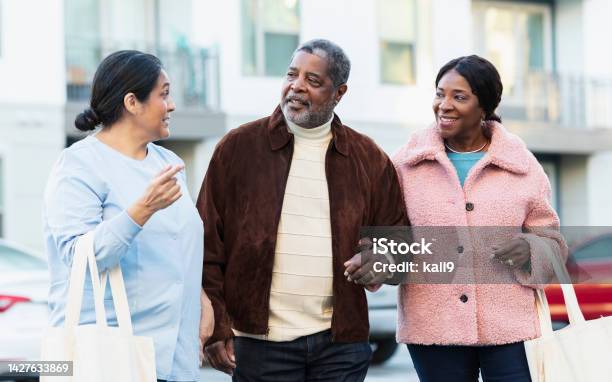 Senior couple and woman walking outdoors, conversing