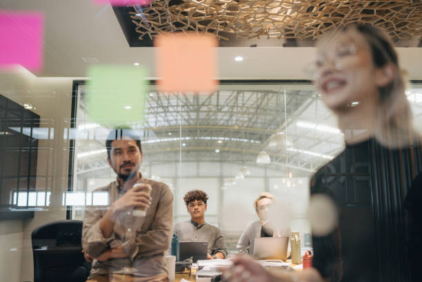 istock Close-up Asian businesswoman write tasks creative ideas and planning on sticky post it note on glass wall. 1427635181