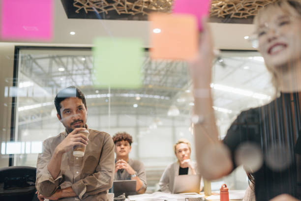 istock Close-up Asian businesswoman write tasks creative ideas and planning on sticky post it note on glass wall. 1427635195