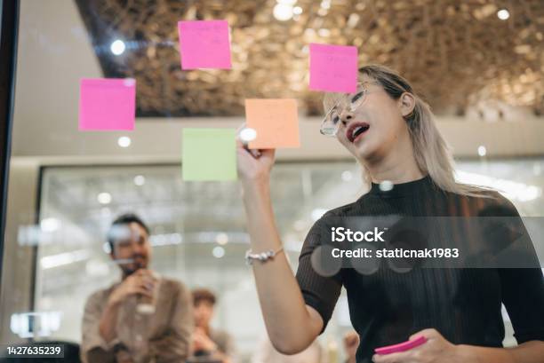 Young Asian Businesswomen Work Attack Sticky Notes On Glass Wall In Boardroom Stock Photo - Download Image Now