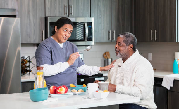 Caregiver with senior African-American man in kitchen