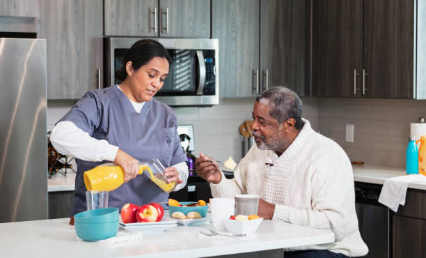 Caregiver with senior African-American man in kitchen