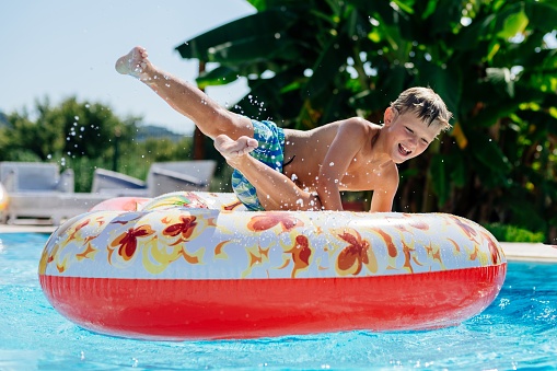 8-year-old boy has a great time on an inflatable mattress at a swimming pool in Corfu, Greece