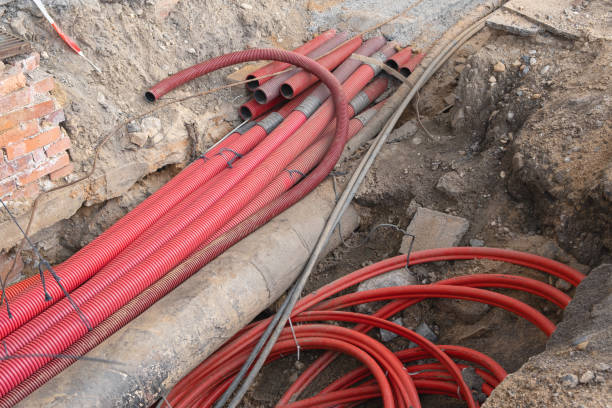 istock Network cables in red corrugated pipe are buried underground on the street. underground electric cable infrastructure installation. Construction site with A lot of communication Cables 1427643897