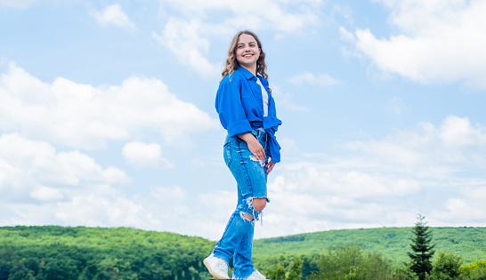 In her own style. girl wearing casual style clothes. spring fashion wear. happy kid on sky background. cheerful retro girl. child having fun. happy childhood. enjoy good weather forecast.