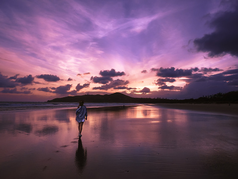 Girl walking towards sunrise at Main Beach in Byron Bay, Australia