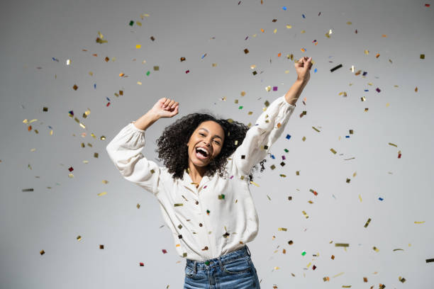 istock Joyful woman laughing, dancing and has fun with falling confetti. Enjoying life, celebration concepts 1427649525