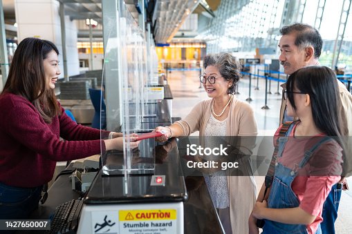 istock Senior Asian woman giving her passport and boarding pass to a airline staff at airport check in counter 1427650007