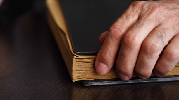 istock A man's hand and an old book on the table 1427650504