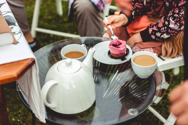istock woman is enjoying a cupcake with a chocolate base and violet icing standing on a beautiful glass table. A white coffee mug is next to it. 1427652174