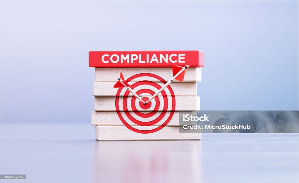 Compliance Concept - Arrows Hitting Bull's Eye Target Symbol And The Compliance Word Written Wood Blocks In Front Defocused Background Arrows hitting bull's eye target and the compliance written wood blocks sitting in front of defocused background. Compliance concept. Obedience Stock Photo
