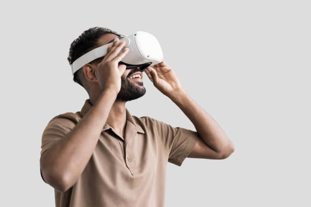 istock Young man using virtual reality eyeglasses headset, isolated on gray background 1427653559