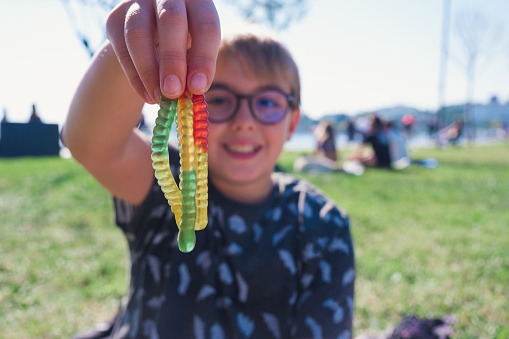 Boy holding chewy gummy worms. Selective focus with copy space.