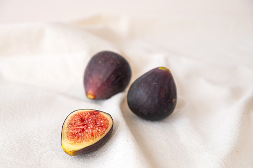 Fresh ripe and sweet figs cut and whole on beige color table cloth.