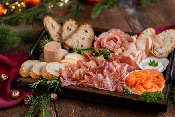 aperitivo tabla de charcutería con jamón, salami, salmón y pan para la celebración festiva de navidad en cocina rústica - cheese still life tray french cuisine fotografías e imágenes de stock