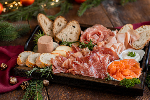Charcuterie Board with ham, salami, salmon and bread for festive Christmas celebration in rustic kitchen