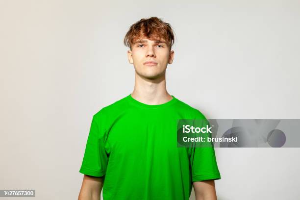 Studio Portrait Of A Caucasian Young Man In A Green Tshirt On A White Background Stock Photo - Download Image Now
