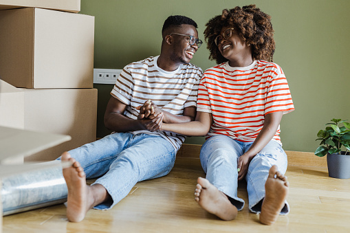Young couple sitting on the floor in a new apartment. They are happy and enjoying new life together.