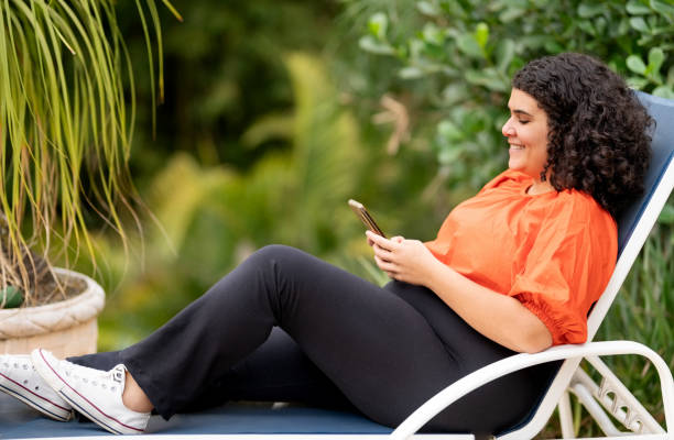 istock Young woman relaxing at the poolside using mobile phone 1427659273