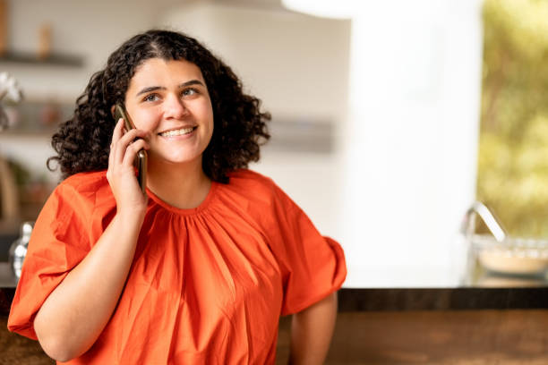 istock Young woman talking on mobile phone at home 1427659278