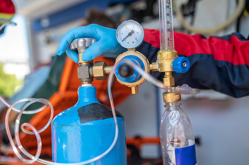 Cropped photo of a paramedic in a nitrile glove opening the oxygen cylinder valve in the emergency vehicle