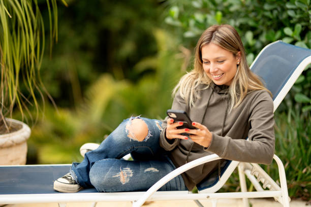 istock Smiling young woman texting messaging outside on her patio 1427668749