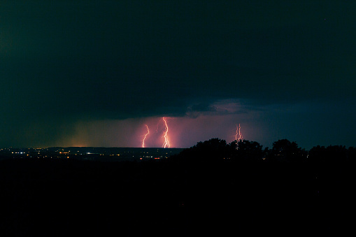 A few flashes from an evening thunderstorm can be seen over a few fields, illuminating the clouds and hitting the ground a few times. The images are color corrected. Perfect for adding a dark element to your story and for all that goes with a scary story or true crime.