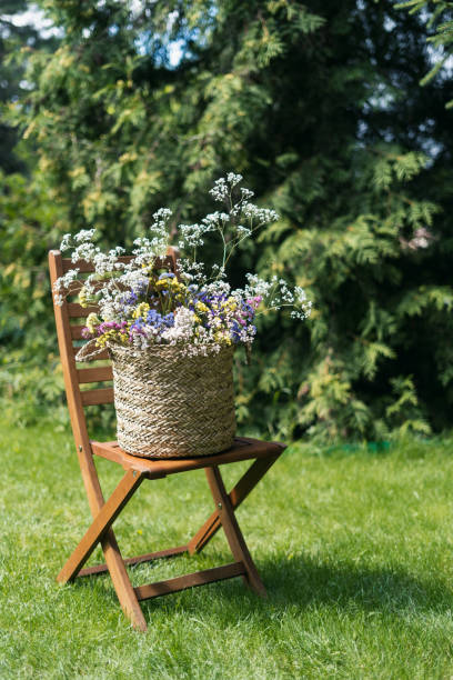 flores en cesta de mimbre en silla al aire libre en verano - wicker basket store gift shop fotografías e imágenes de stock