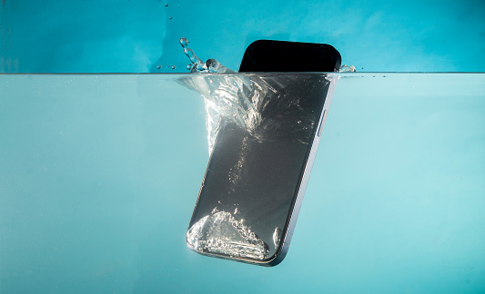 Mobile phone sinking into water - concept of risk and default.