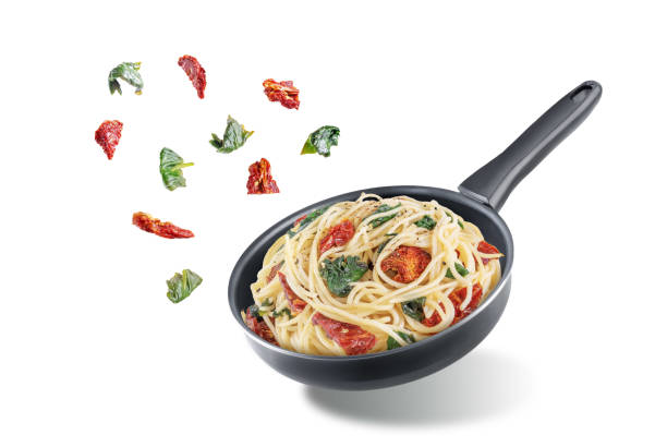 istock Dried tomato spinach Pasta in a pan on a white isolated background 1427672087