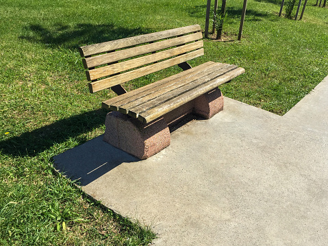 Empty wooden park bench in the public park at sunny day