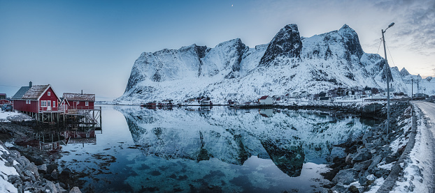 Panorama view of Fishing village on coastline and snowy mountain range in winter on gloomy day at Lofoten Islands, Norway