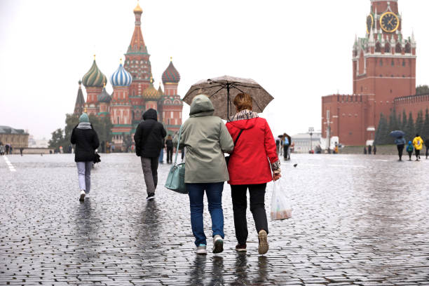 llueve en moscú, dos mujeres con un paraguas caminan por una plaza roja. día nublado, tiempo lluvioso en otoño rusia - moscow russia russia red square st basils cathedral fotografías e imágenes de stock