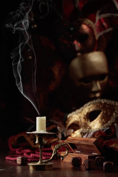 istock Extinguished candle, dice, and carnival masks on an old wooden table. 1427680701